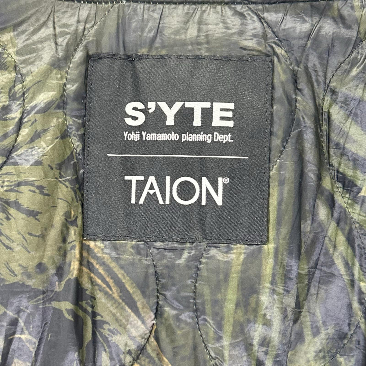 S'YTE サイト 【×TAION】UB-Y04-921 ブラック×オリーブグリーン DAHLIA CAMOUFLAGE QUILTED DOWN REVERSIBLE LONG MA-1 リバーシブル ブル ジャケット