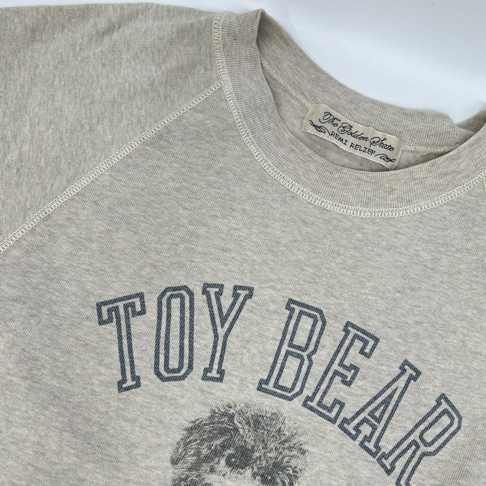 REMI RELIEF レミレリーフ ×HUG O WaR 25SS オートミール/ベージュ コットン TOY BEAR ヴィンテージ加工 天竺ラグランスリーブTシャツ トップス